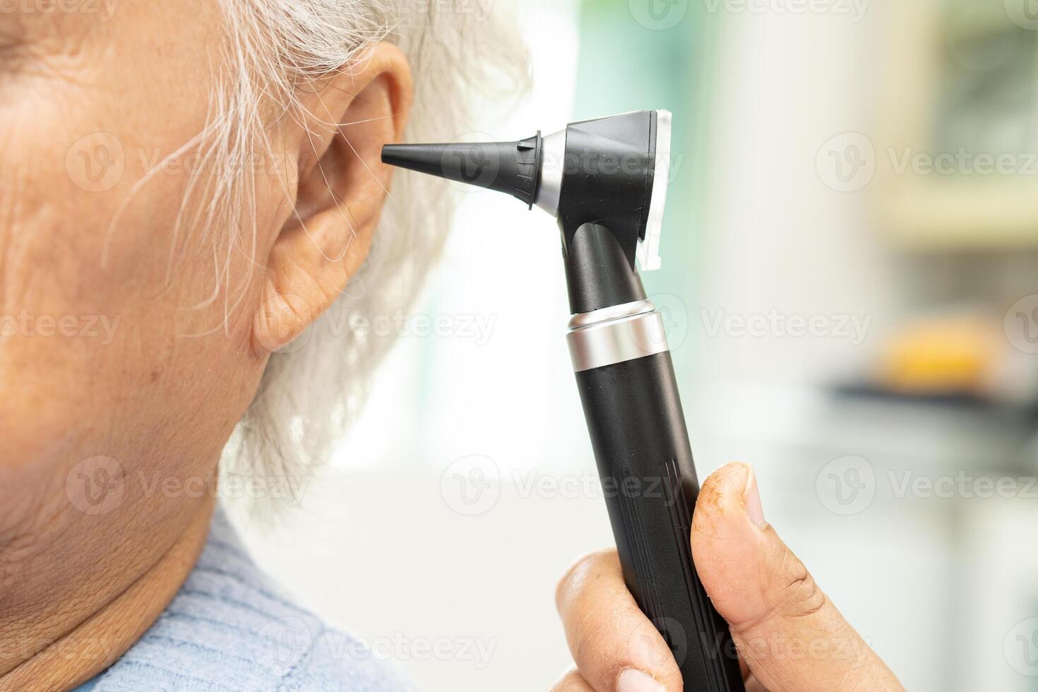 Audiologist or ENT doctor use otoscope checking ear of asian senior woman patient treating hearing loss problem. photo