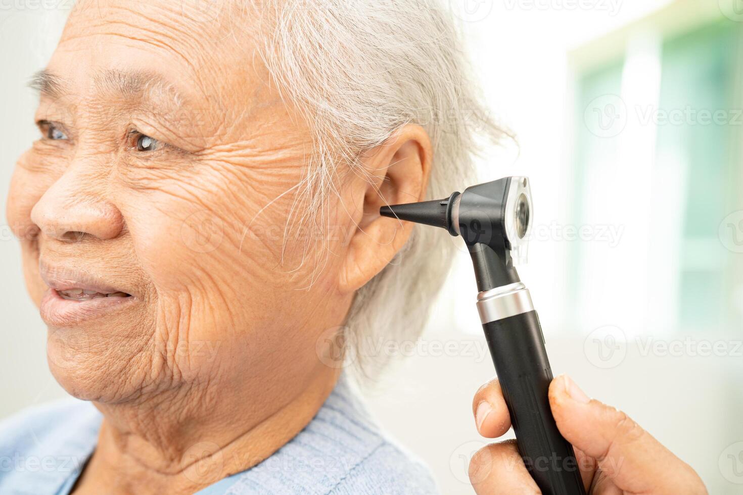 Audiologist or ENT doctor use otoscope checking ear of asian senior woman patient treating hearing loss problem. photo