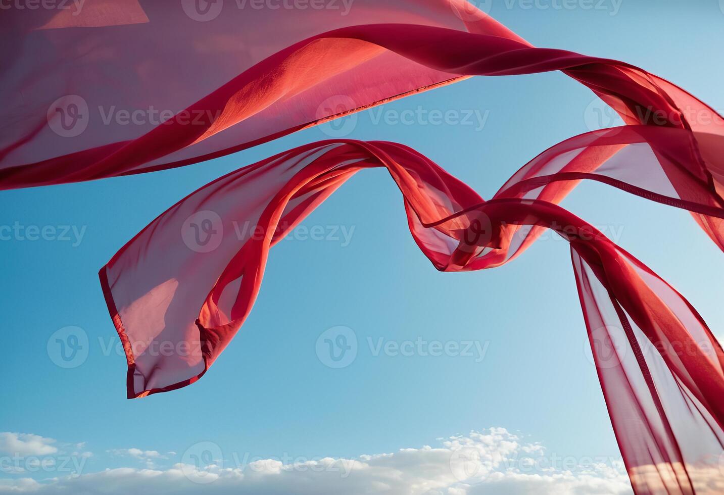 Flying transparent red fabric wave on blue sky background and illuminated by sunlight photo