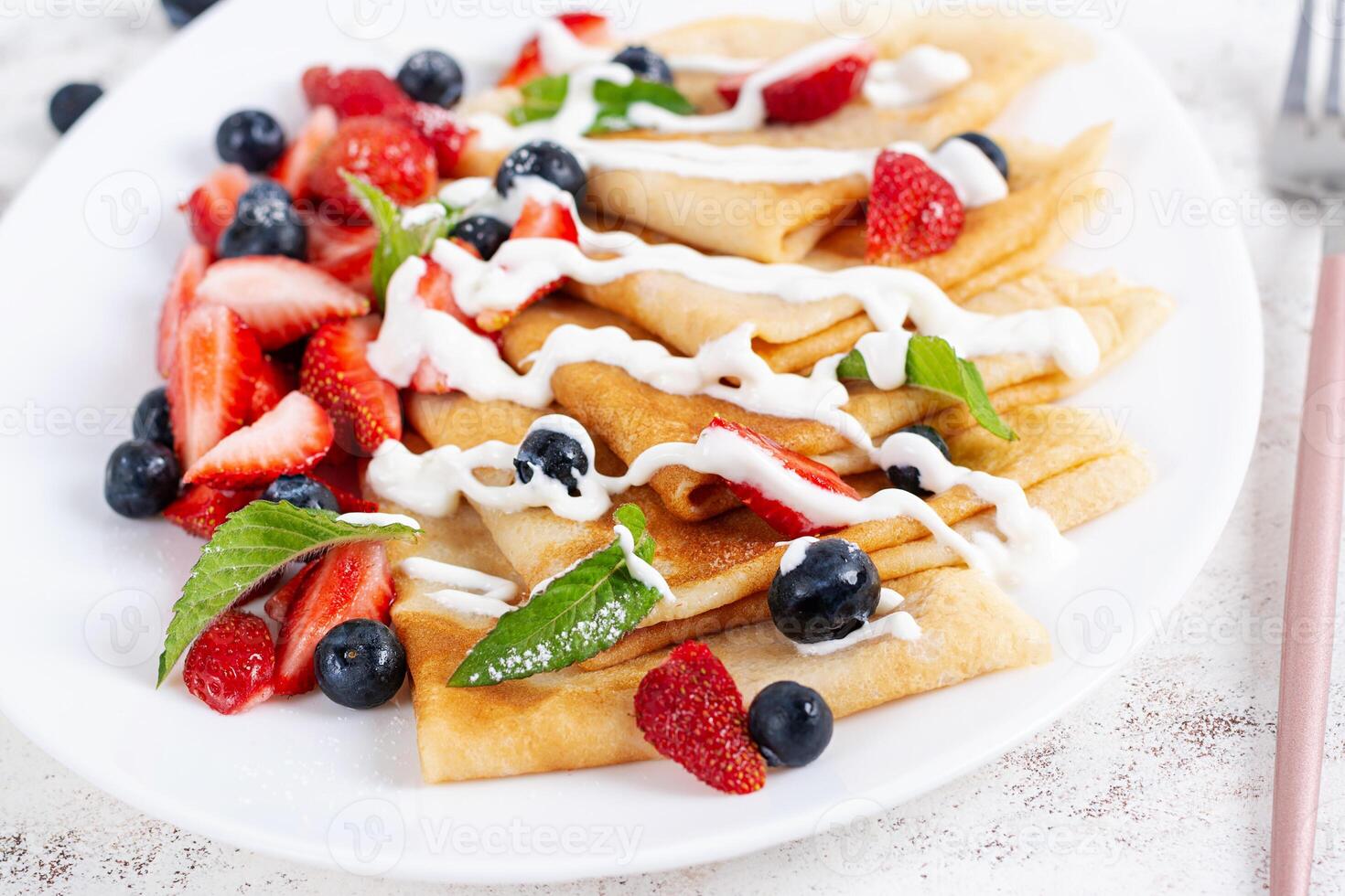 Pancakes with berries and sour cream. Healthy breakfast. Late breakfast. Crepes photo