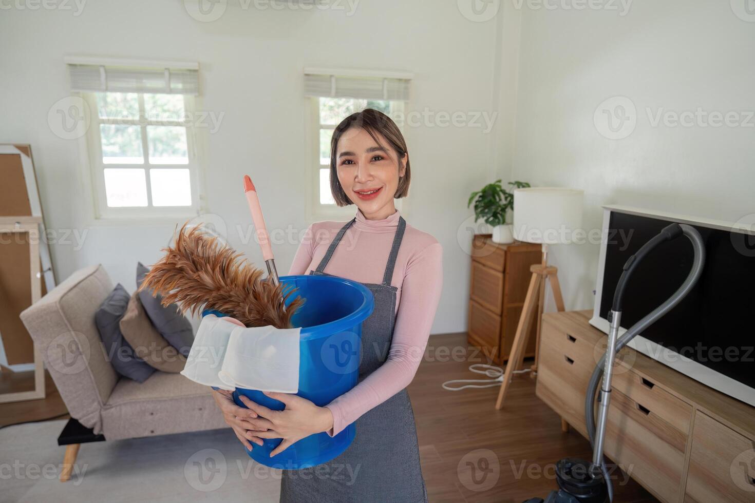 Cheerful Housekeeper Holding Cleaning Supplies in a Modern Living Room Ready for Housekeeping Duties photo