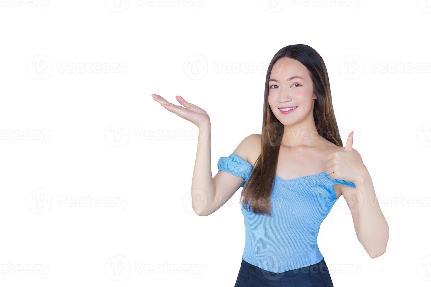Young beautiful Asian woman in a blue shirt is acting thumb up as good symbol and another hand shows as presenting something while isolated white background. photo