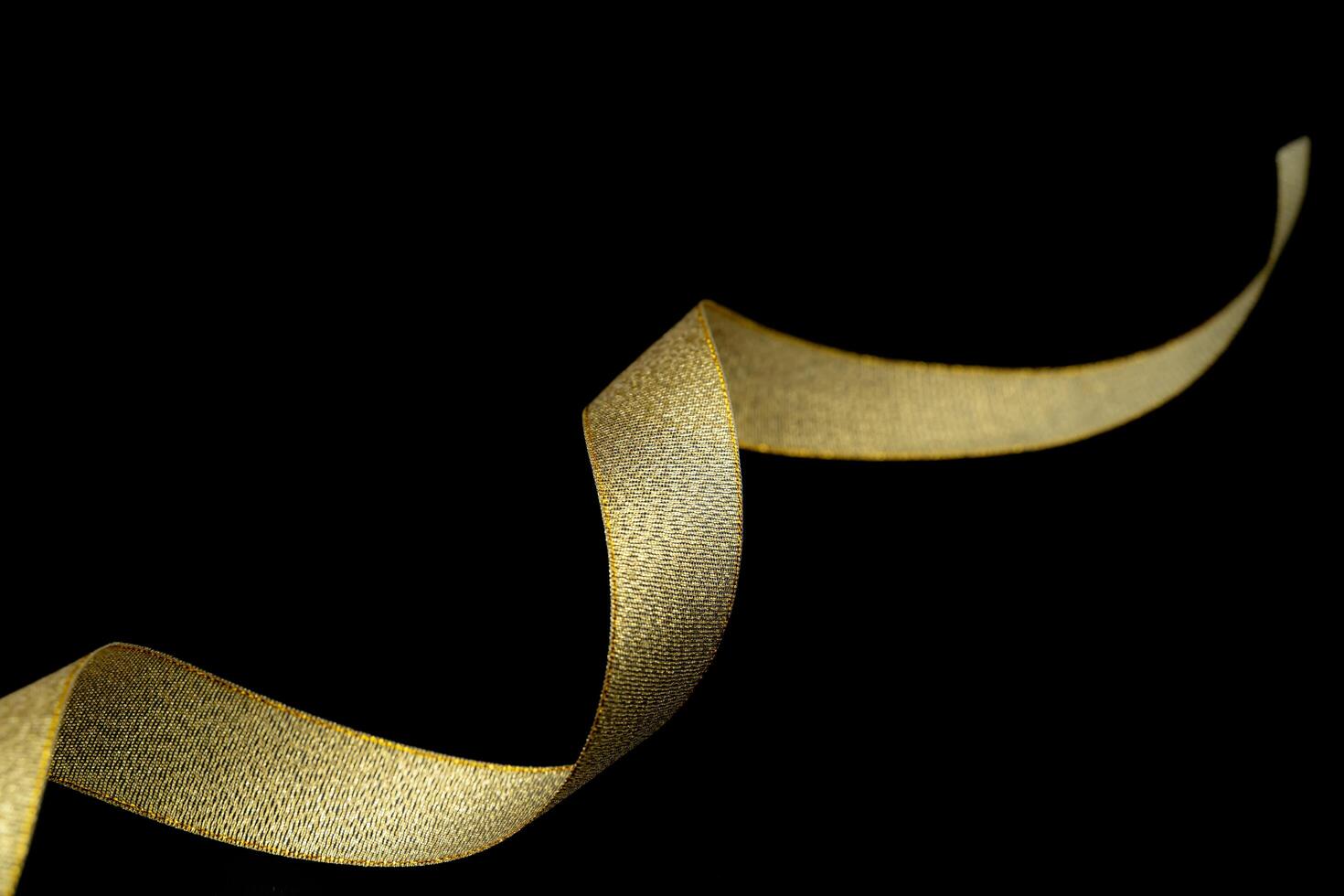 gold fabric ribbon on black background. Golden ribbon isolated on black background and texture. photo