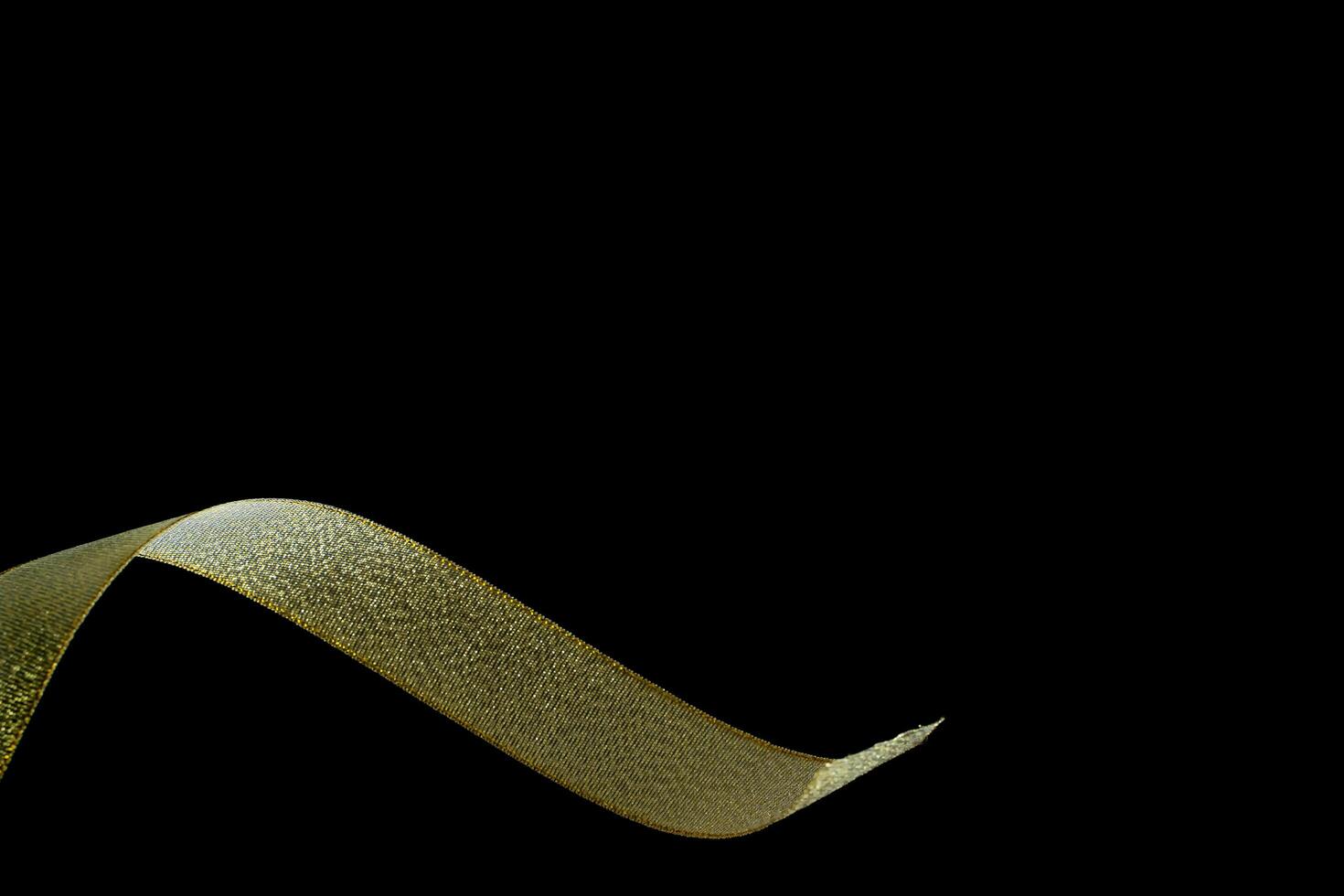 Golden ribbon isolated on black background and texture, gold fabric ribbon on black background. photo