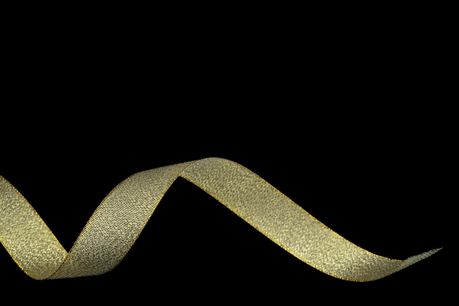 Gold gift wrap ribbon on black fabric background. Holiday, celebration. With copyspace. Golden ribbon isolated on black background and texture photo