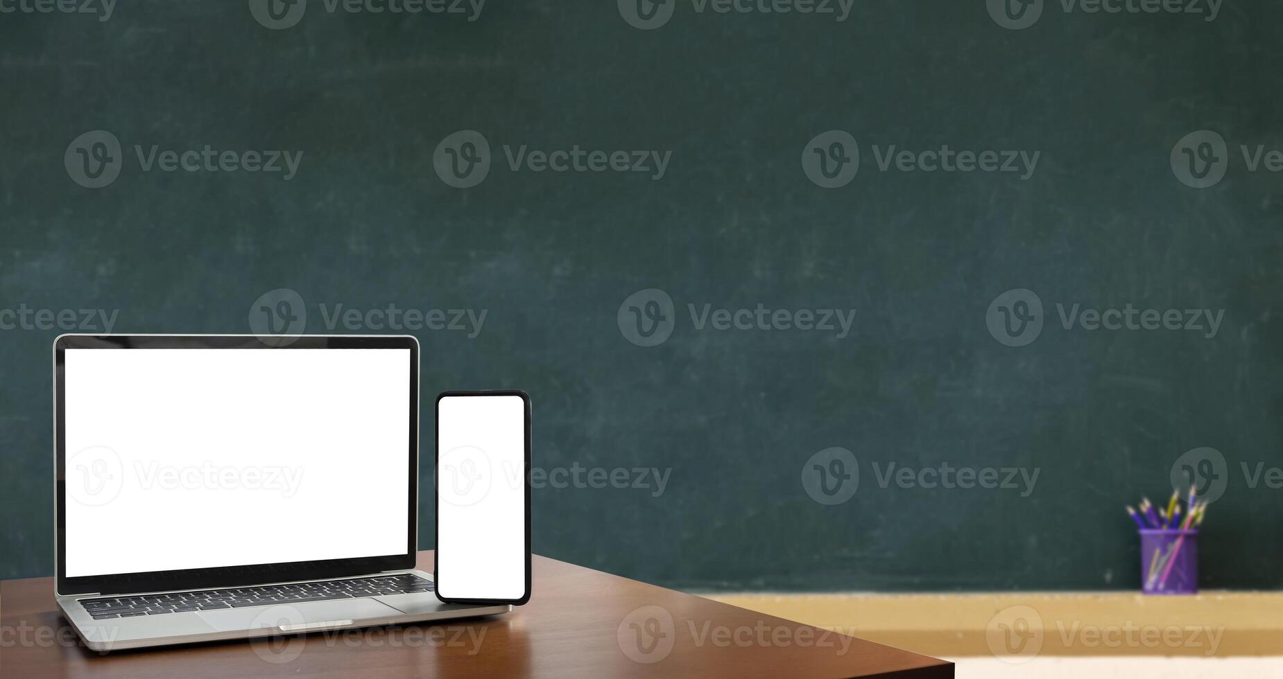 Laptop, smartphone, blank screen lies on wooden table for foreground. Blackboard is Empty, Education is important for everyone, because it helps to succeed. To stimulate teaching. photo