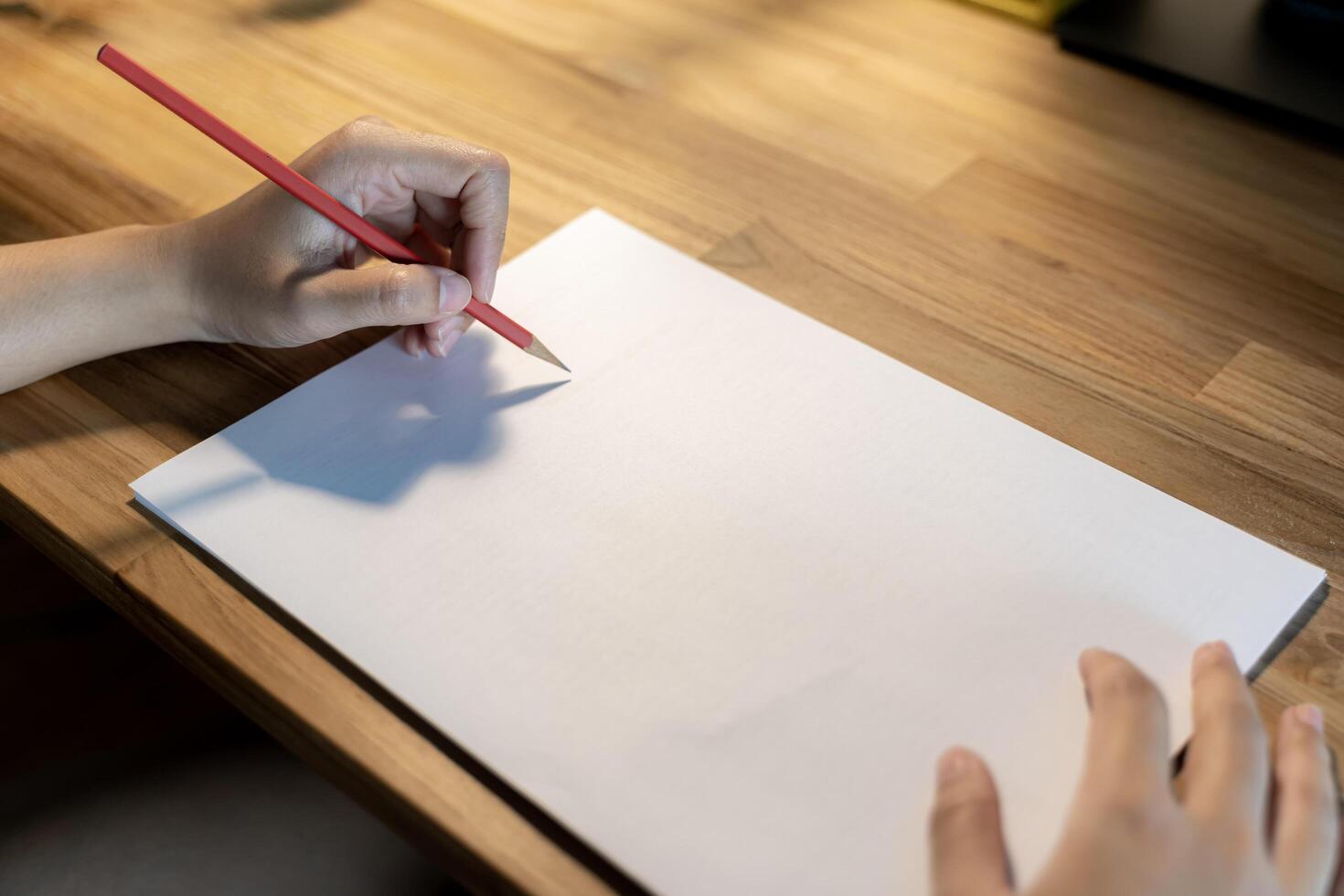 Woman writing something on sheet of paper at workplace in evening.Free space can contain advertising messages. photo