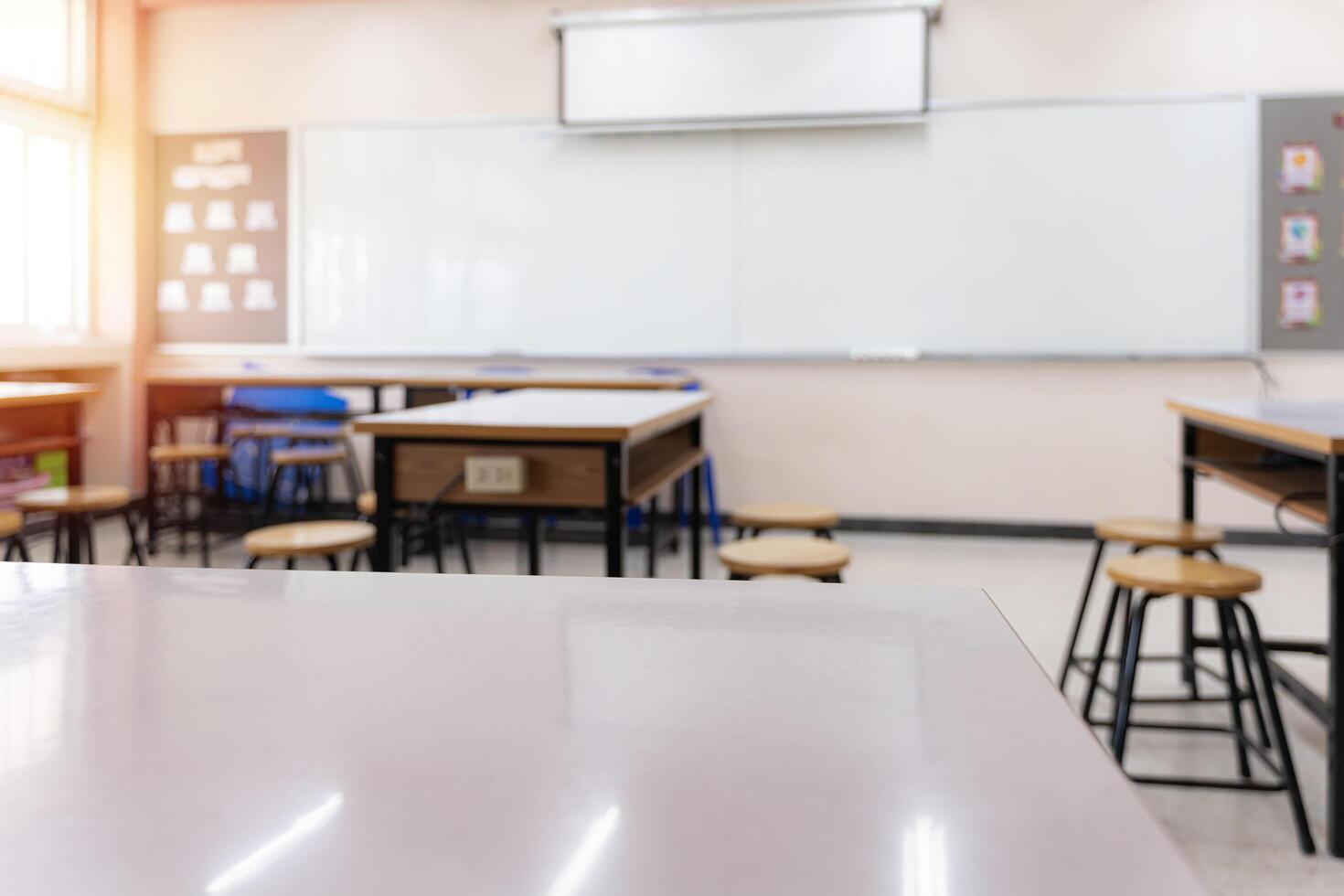 Cropped shot of table and copy space in blurred study room.Empty classroom or presentation room interior with desks photo