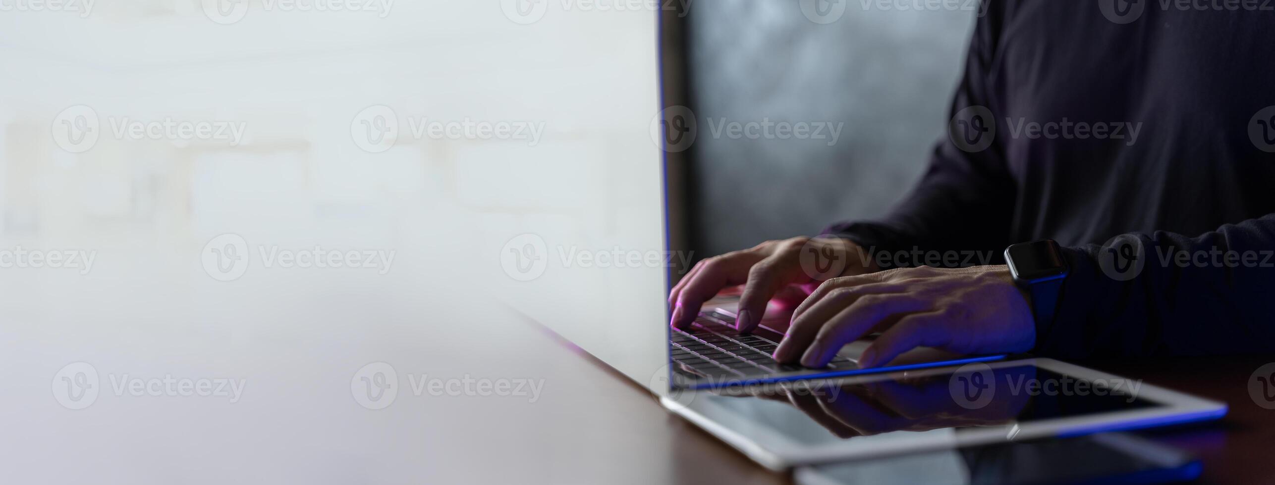 Side view of male hands typing on laptop keyboard. Young businessman using laptop on table, blurred background. Wide landscape banners with blank space photo