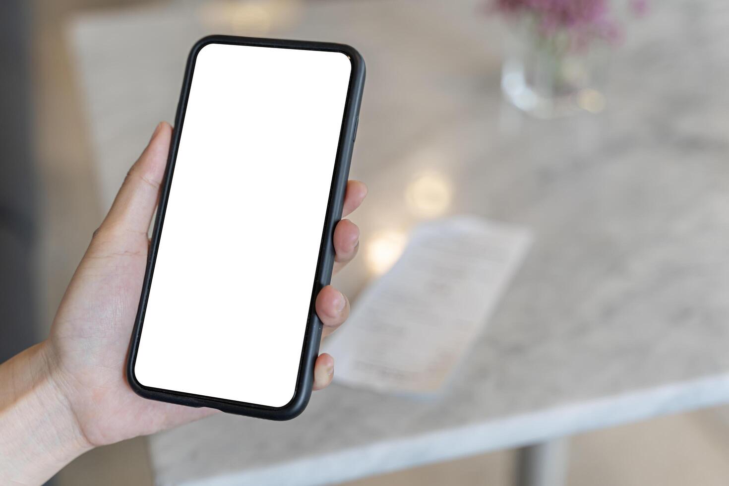 Close up woman university student holding smartphone with empty mock up copy space screen background for promotional content while sitting in coffee shop during rest in winter day. photo