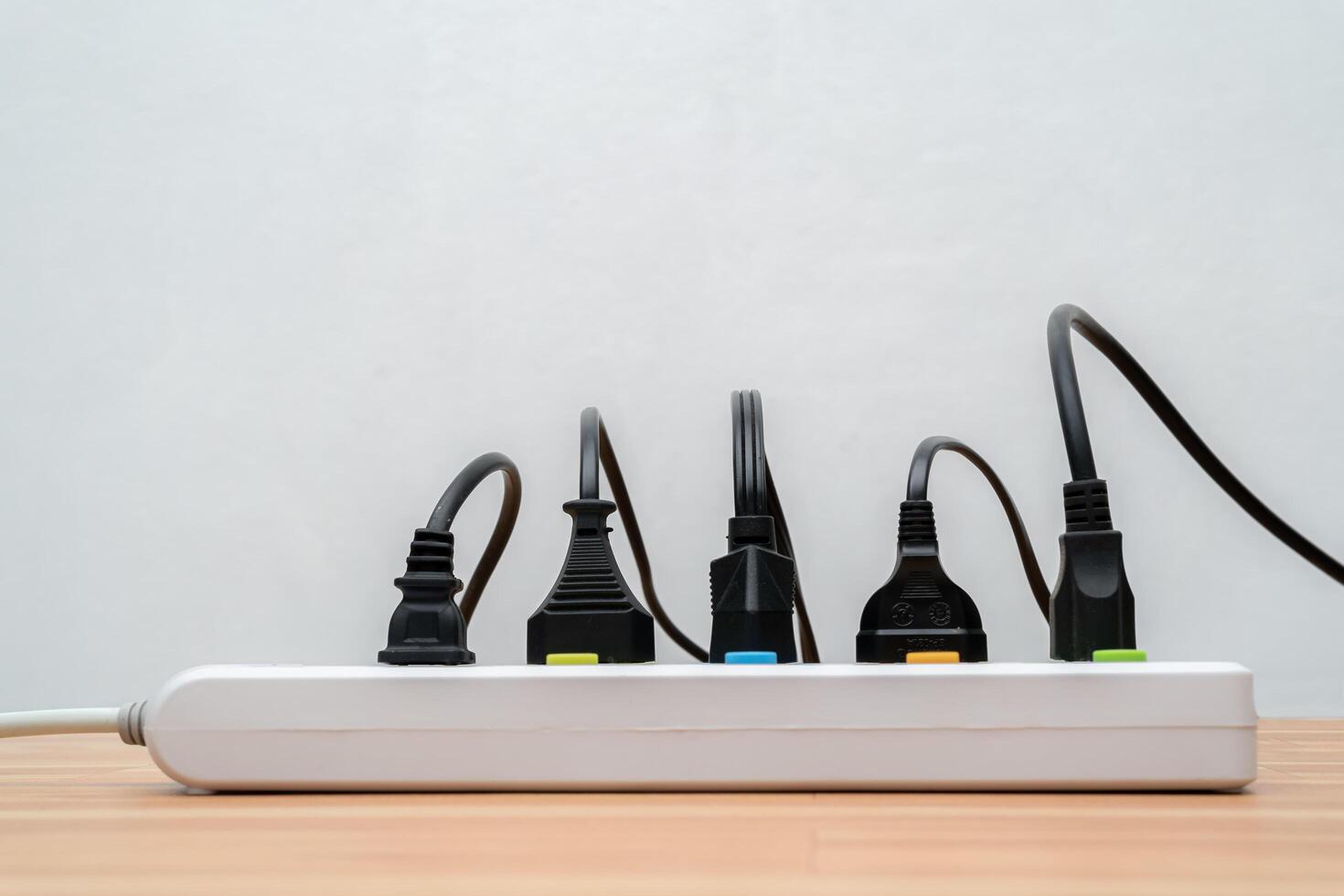 Surge protector with connected white wires of electrical appliances. Free space. Socket strip and connected plugs on background. photo