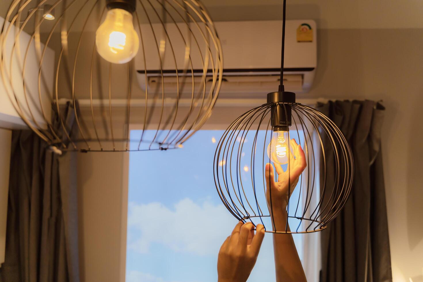 woman changing lightbulb in a lamp. Hands installing LED bulb in lamp, chandelier. An electrician is installing spotlights on the ceiling. photo