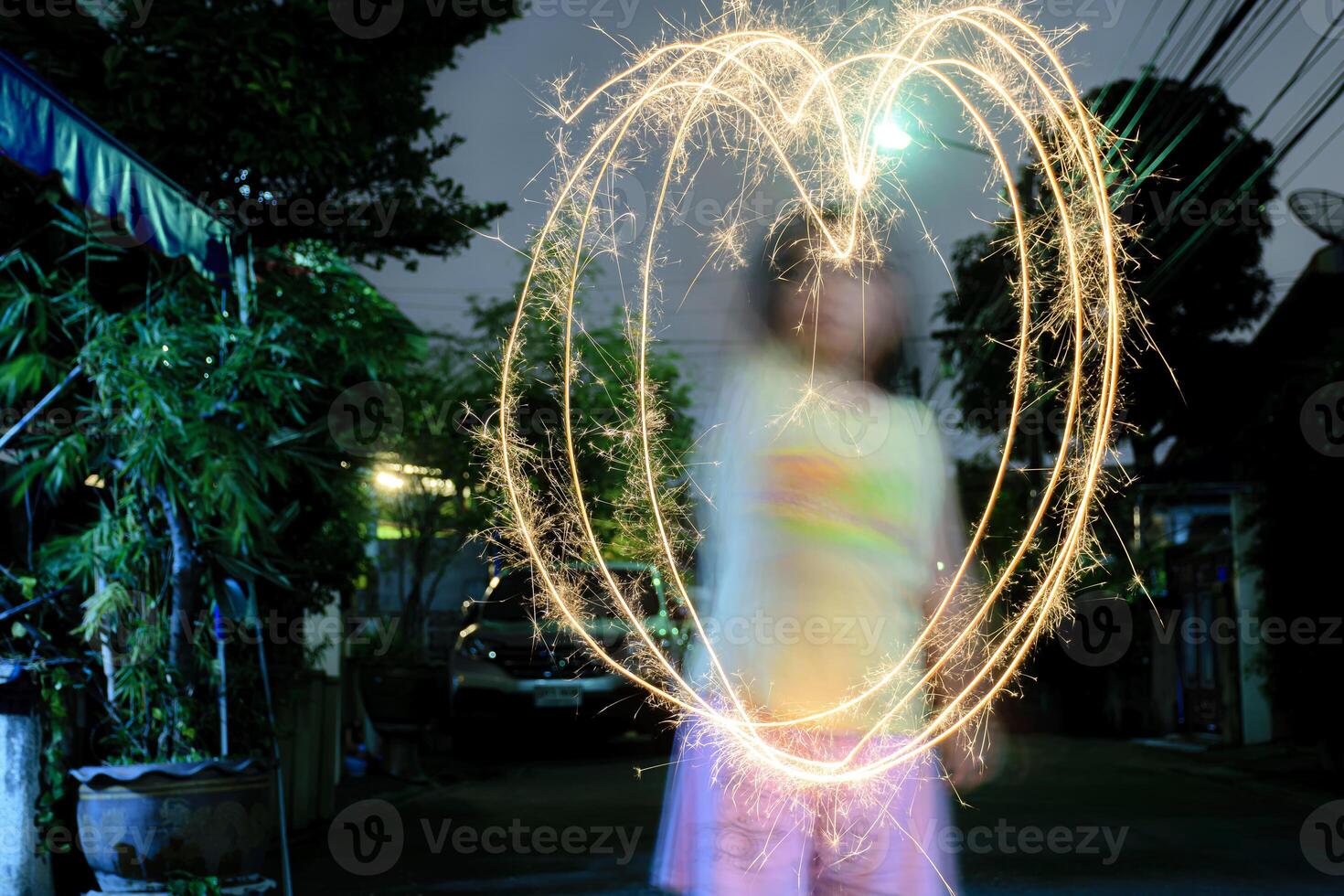 A large heart drawn out with a sparkler. Girl draws out a heart using a sparkler photo