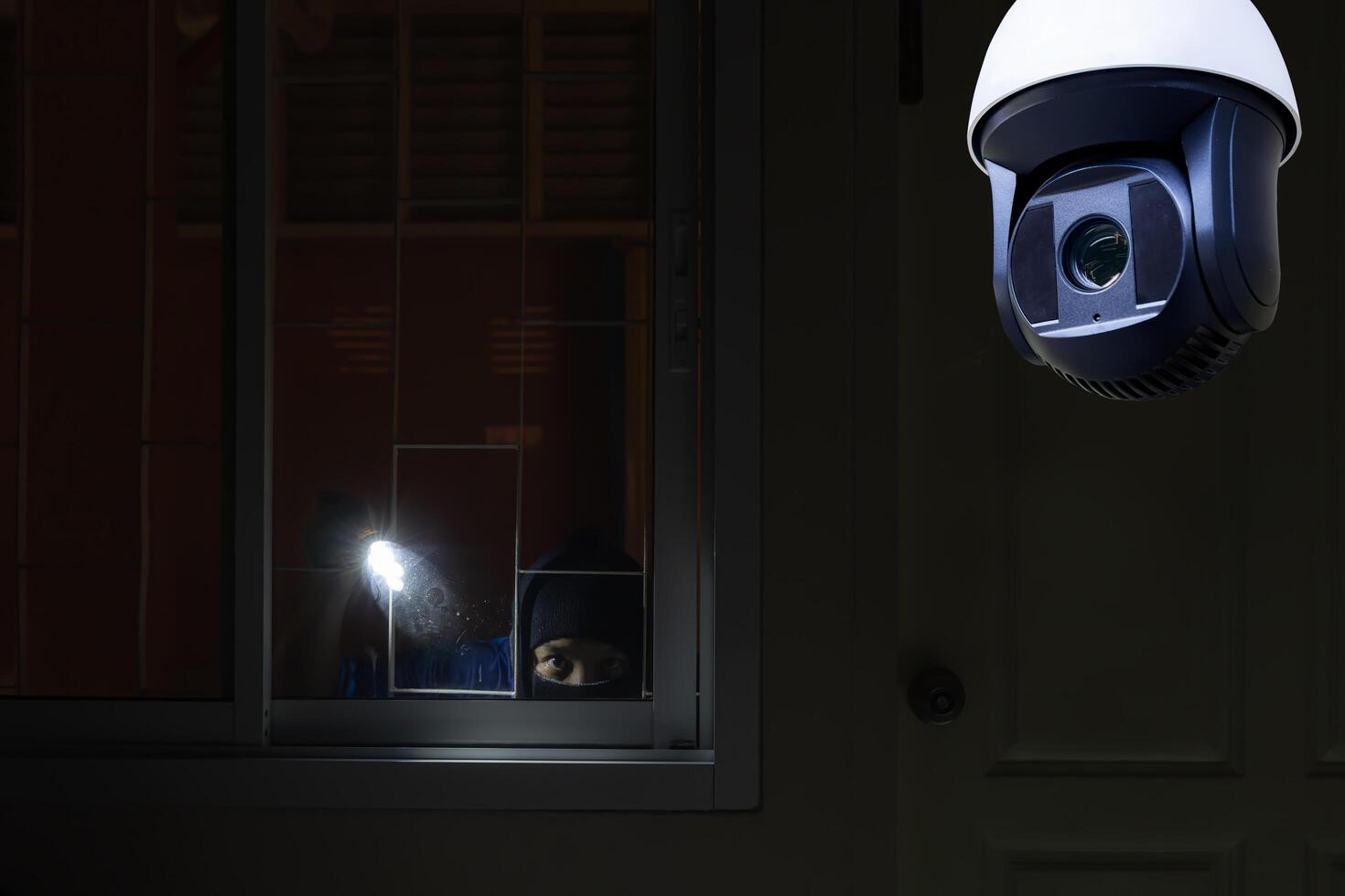 CCTV Camera Showing A Burglar Stealing Things In The House. Thief wearing black suit with balaclava and glove being caught by CCTV photo