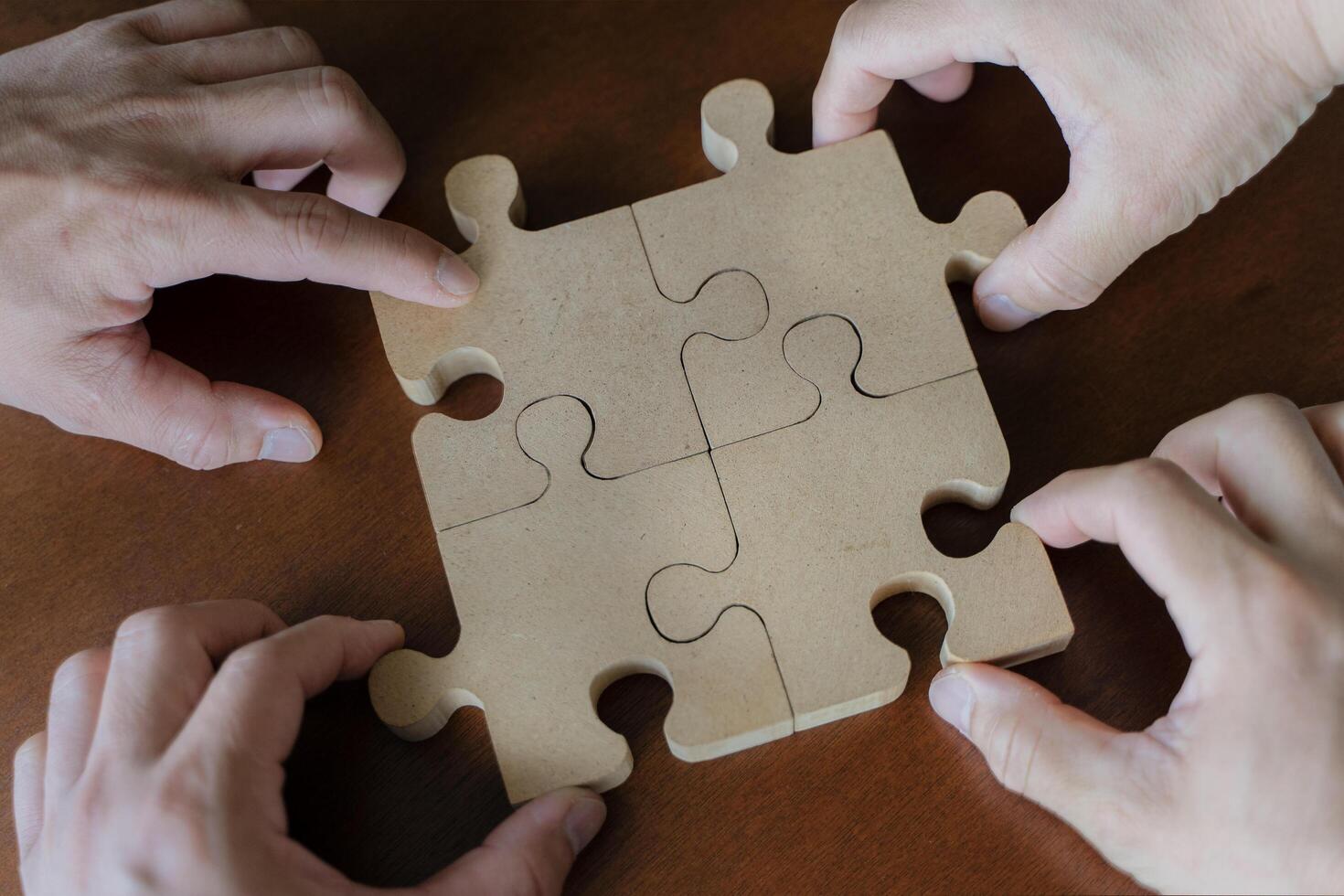 Business people team sitting around meeting table and assembling wooden jigsaw puzzle pieces unity cooperation ideas concept photo
