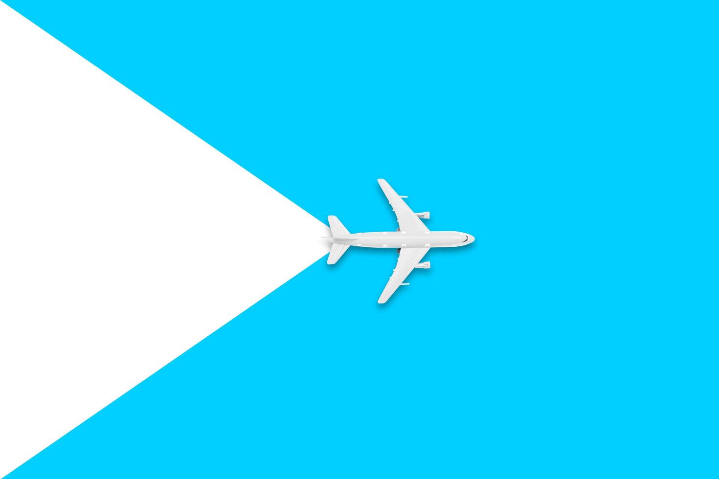 Flat lay of miniature toy airplane on white and yellow background. Travel items on a blue background. photo