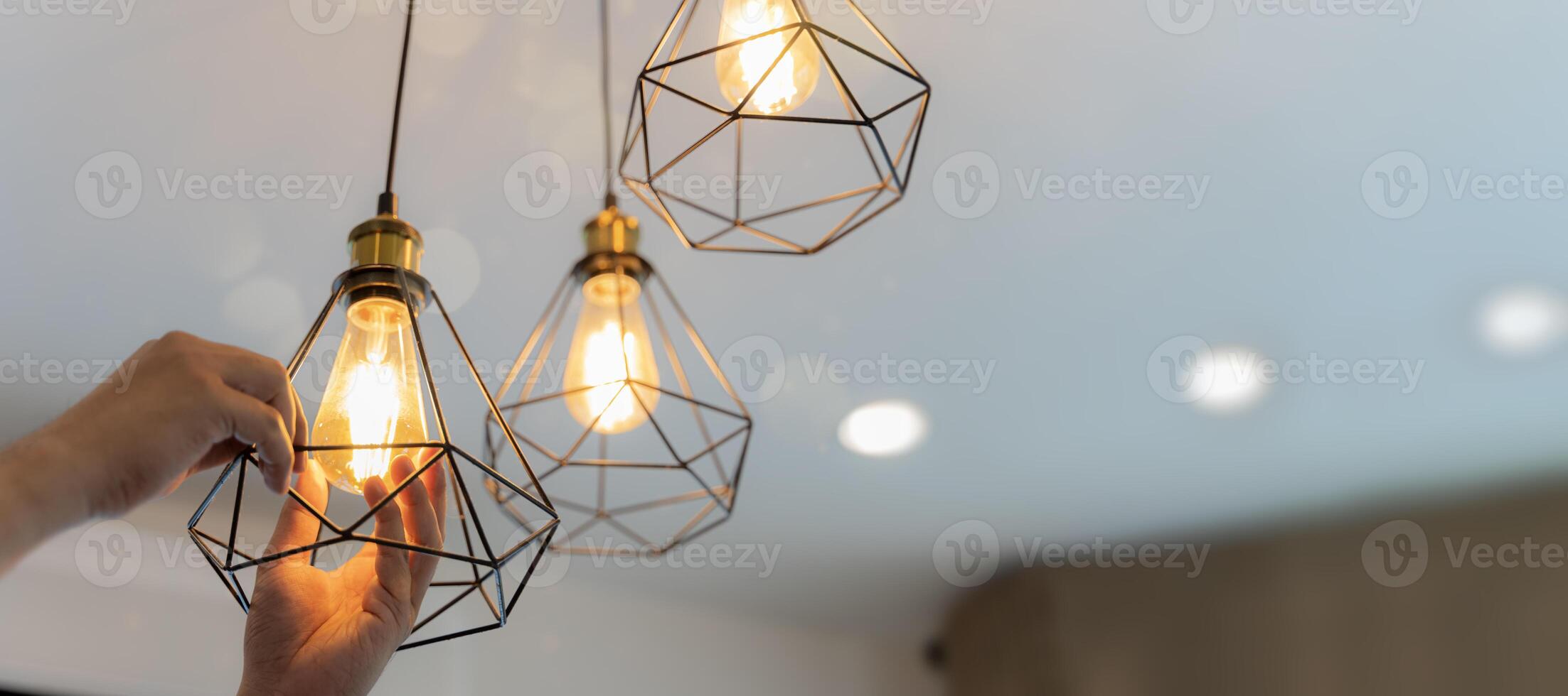 An electrician is installing spotlights on the ceiling. Handyman choosing between energy save and cheap incandescent lamp while changing light. photo