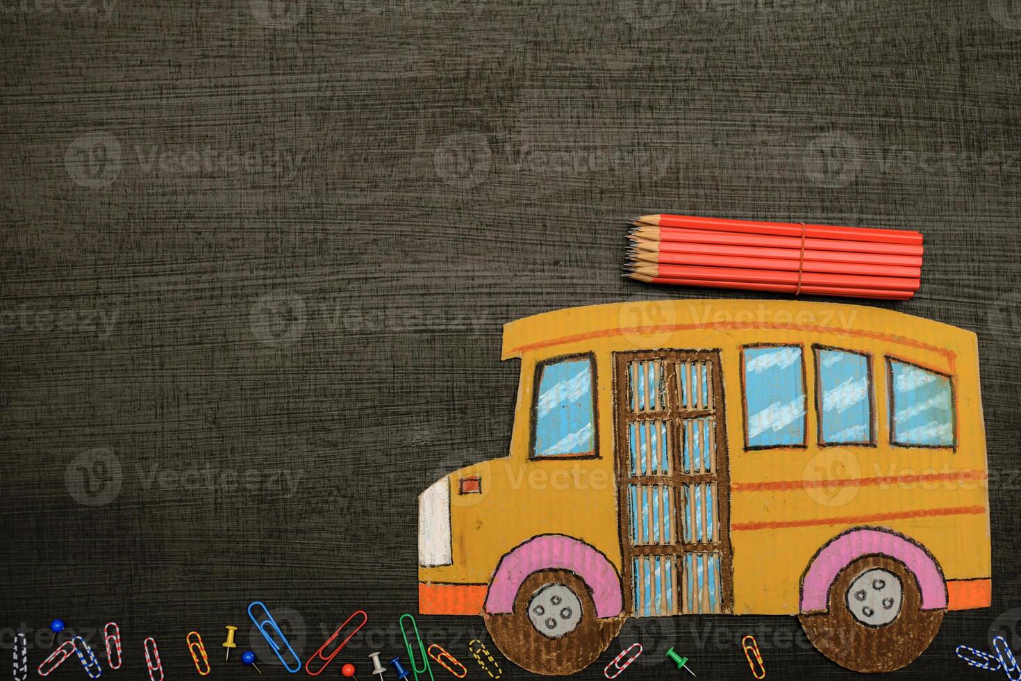 Education and back to school concept Top view of cardboard school bus and pencils, stationery with chalkboard background photo