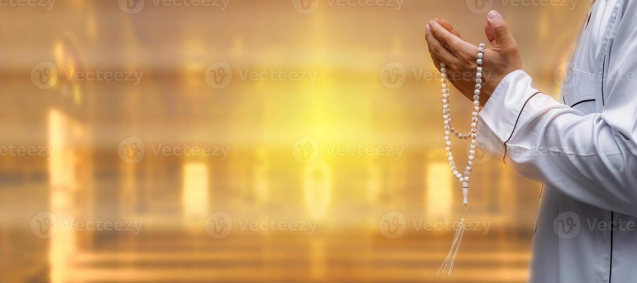 Muslim man raise their hands to pray with Tasbeeh in mosque, indoors.Focus on hands.Religious asian muslim man praying.End of fasting.Hari Raya day. photo