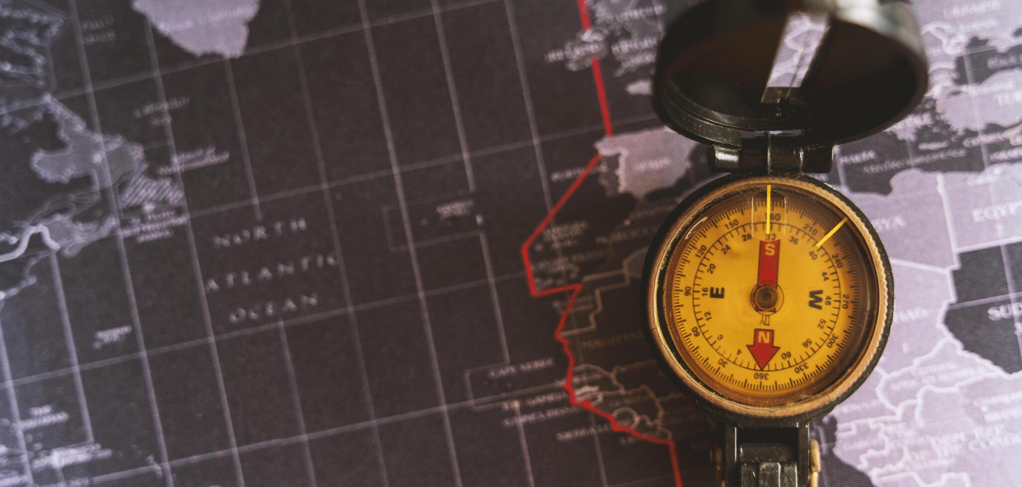 Old compass discovery on vintage paper antique world map background, Retro style cartography travel geography navigation. photo