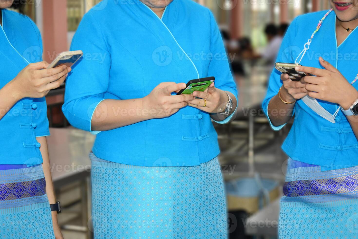 A group of friends stand in the background at a restaurant using smart cell phones. People are addicted to new technology trends. photo