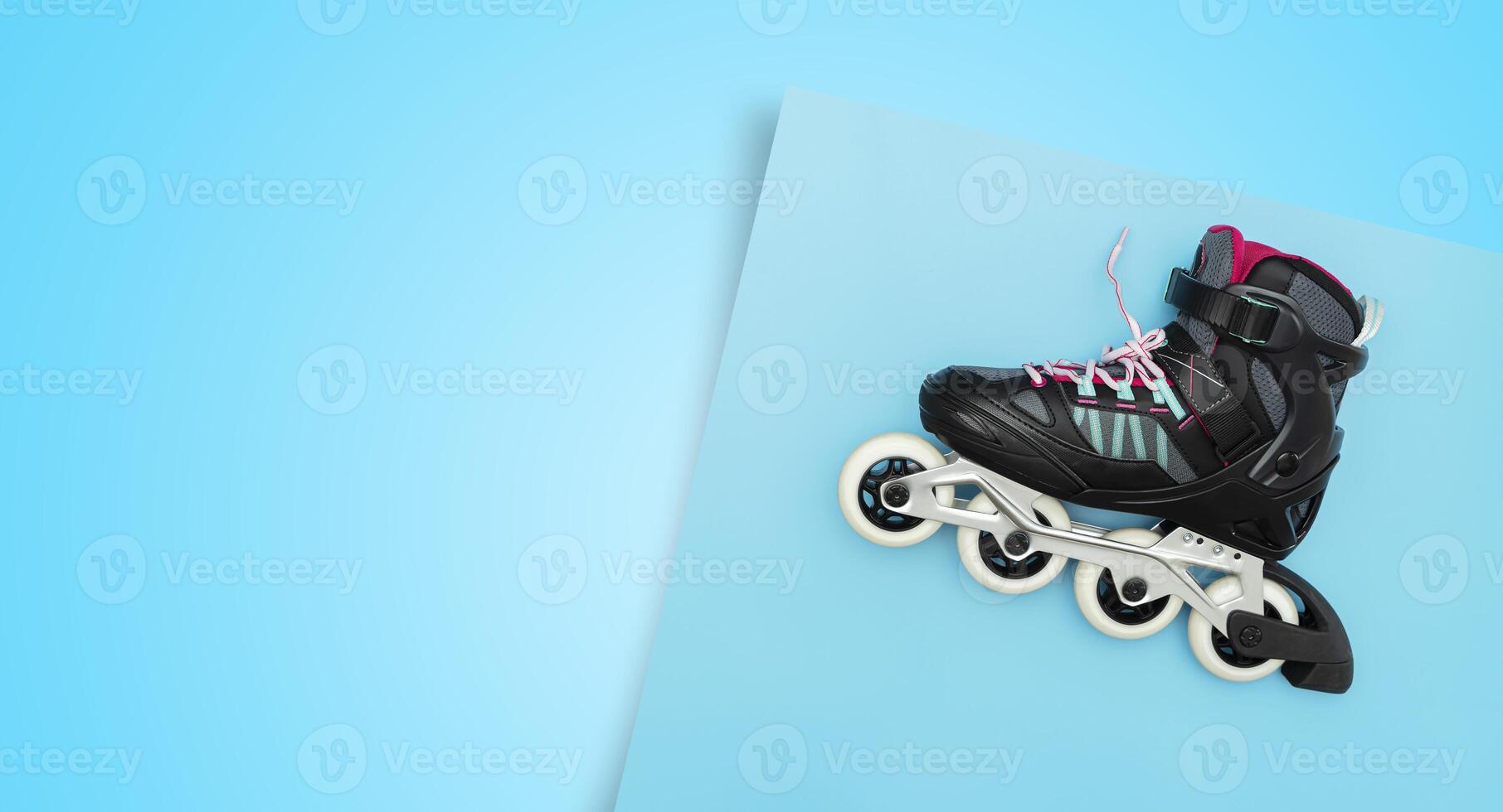 Black single row roller skates on a blue background. Stylish roller skates on blue background, top view. photo