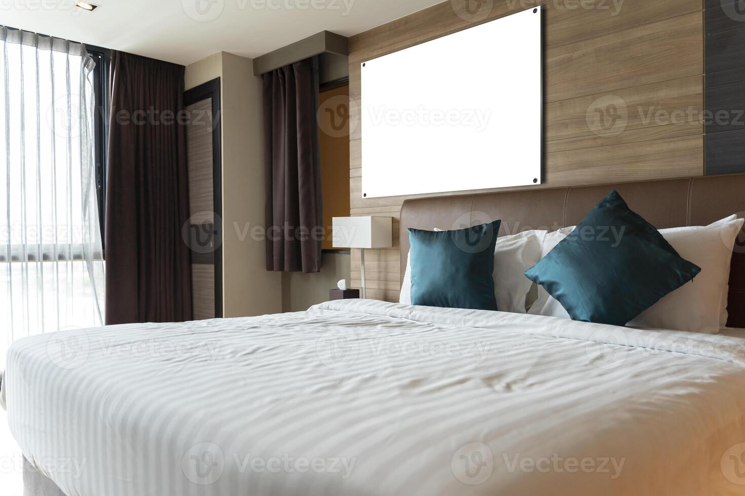 A large blank white framed poster in a black frame over the head of a bed in a luxury hotel bedroom. Stylish waiting area with wooden floors photo