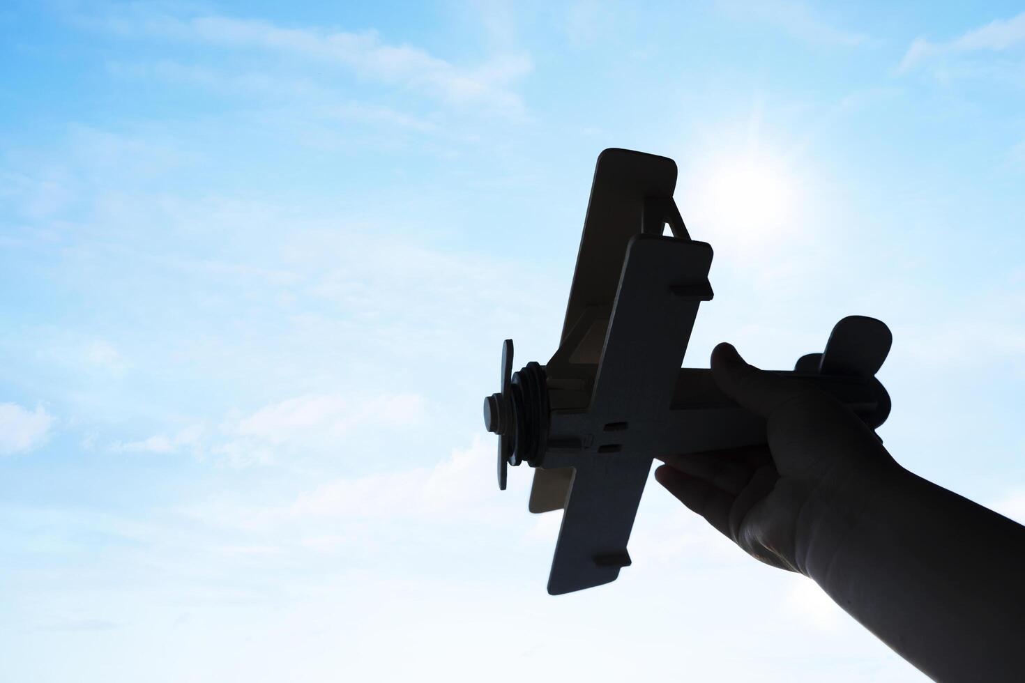Child's hand holding a Toy balsa wood airplane in the sky. photo