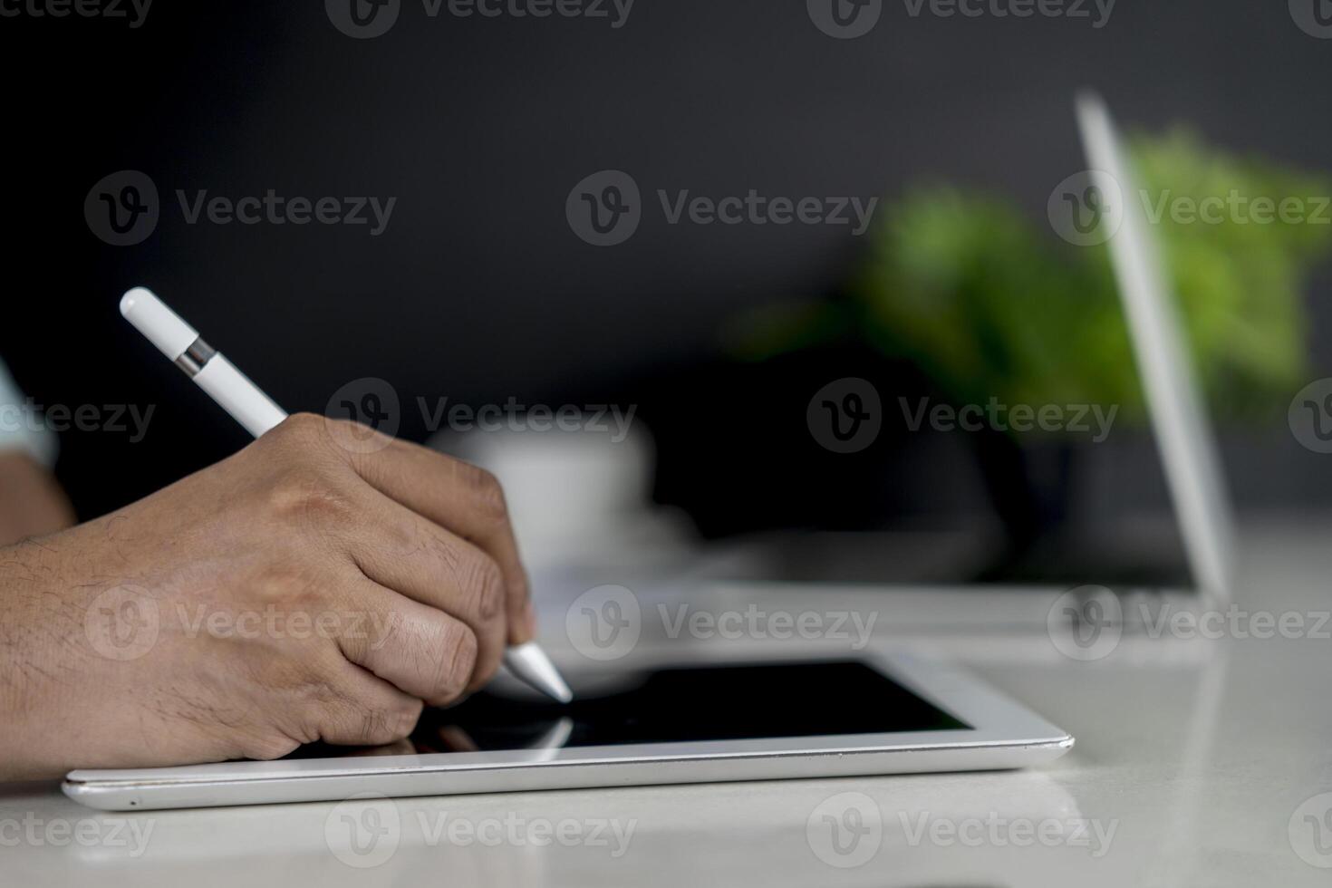 Closeup hand signing or using digital pen on computer tablet on the desk photo