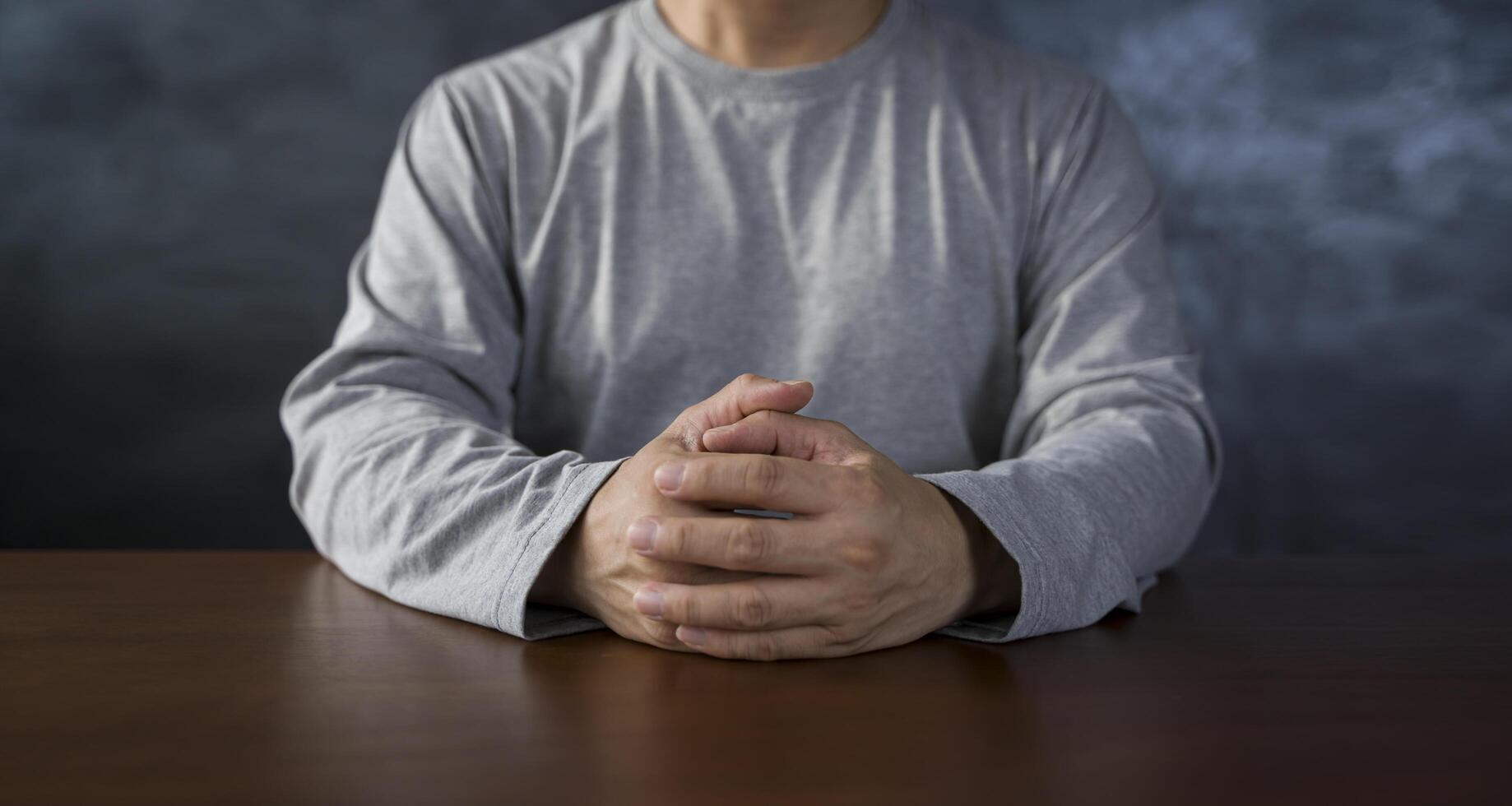 Interlocked fingers, white male hands interlocked on black rustic wood table close up. front view. a man is waiting for negotiations. photo