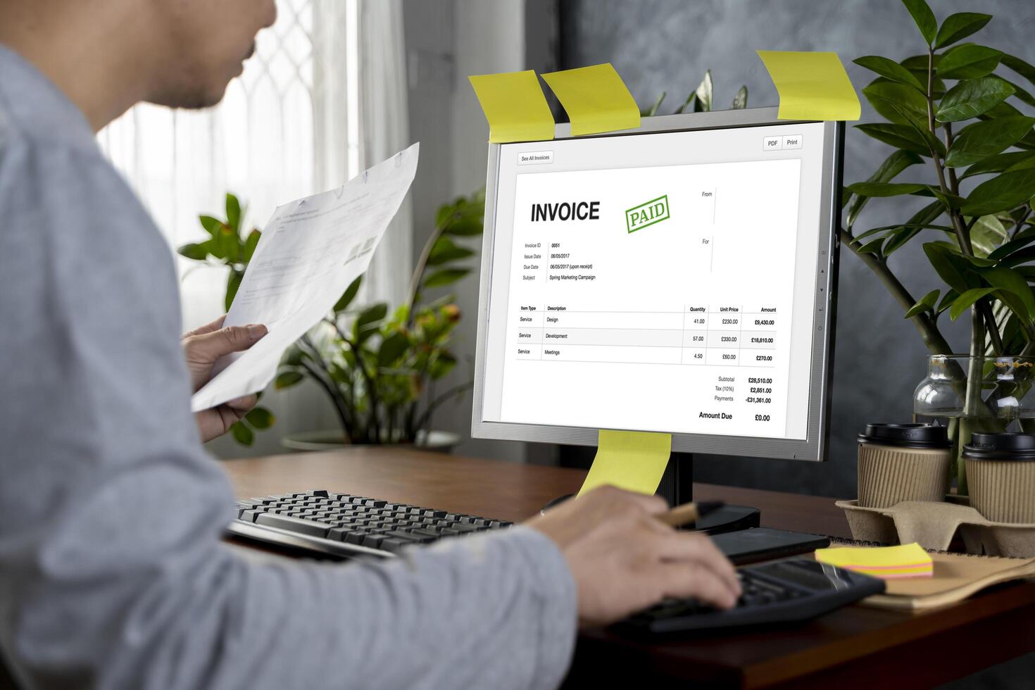 Hands of businessman analyzing invoice on laptop while checking bills. Rear view of latin man checking invoice while matching them on computer. photo