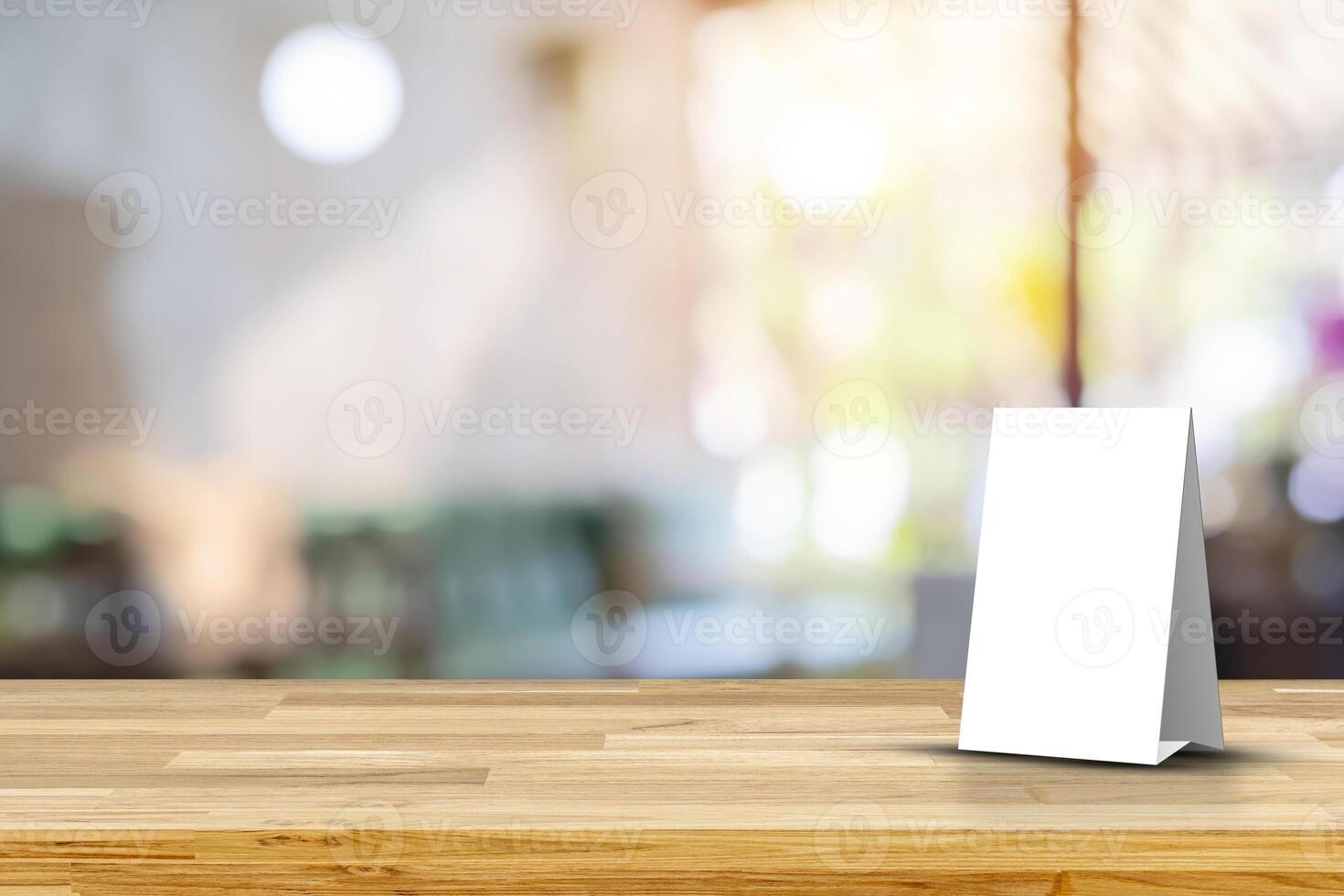 Stand Mock up Menu frame tent card blurred background design key visual layout. Empty wood table top with cafe restaurant interior blur background photo
