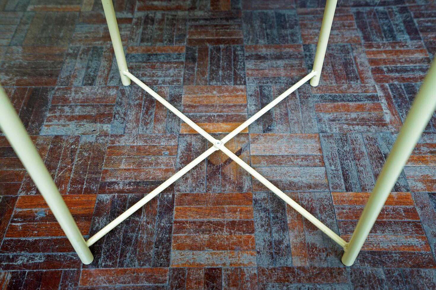Close up metal table legs on old wooden parquet flooring photo