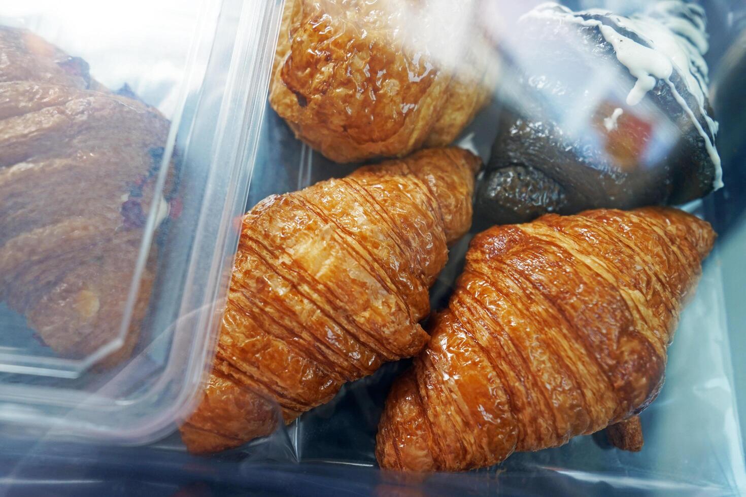 A plastic box of plain butter and dark chocolate croissants photo