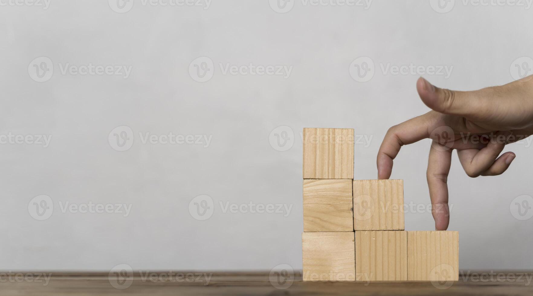 Woman hand finger walk on stacked wooden block like stairs, rises on the steps. Business development photo