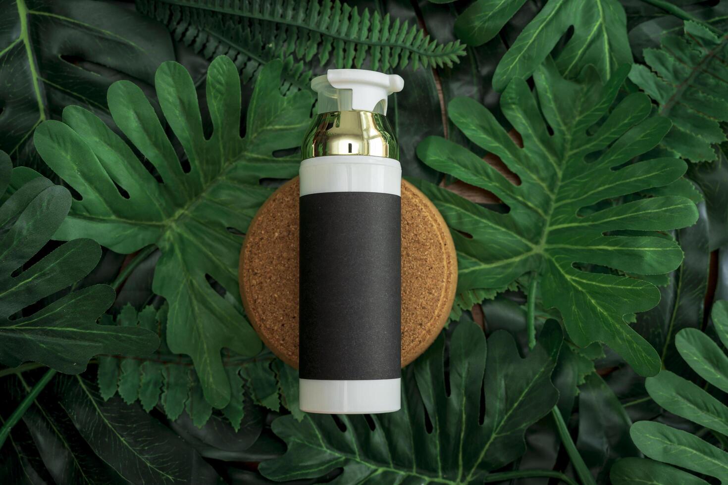 cosmetic product presentation. Cosmetic jar and green leaf on color background. White product bottle, golden cap, black paper product label. photo