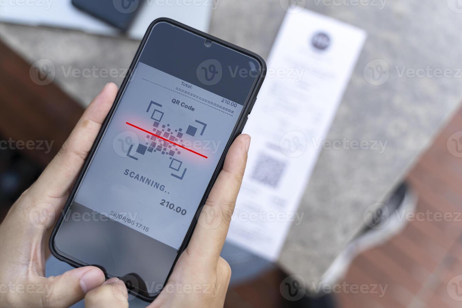Hands of young woman using mobile smart phone for scan and payment online with family budget cost bills on desk in home office photo
