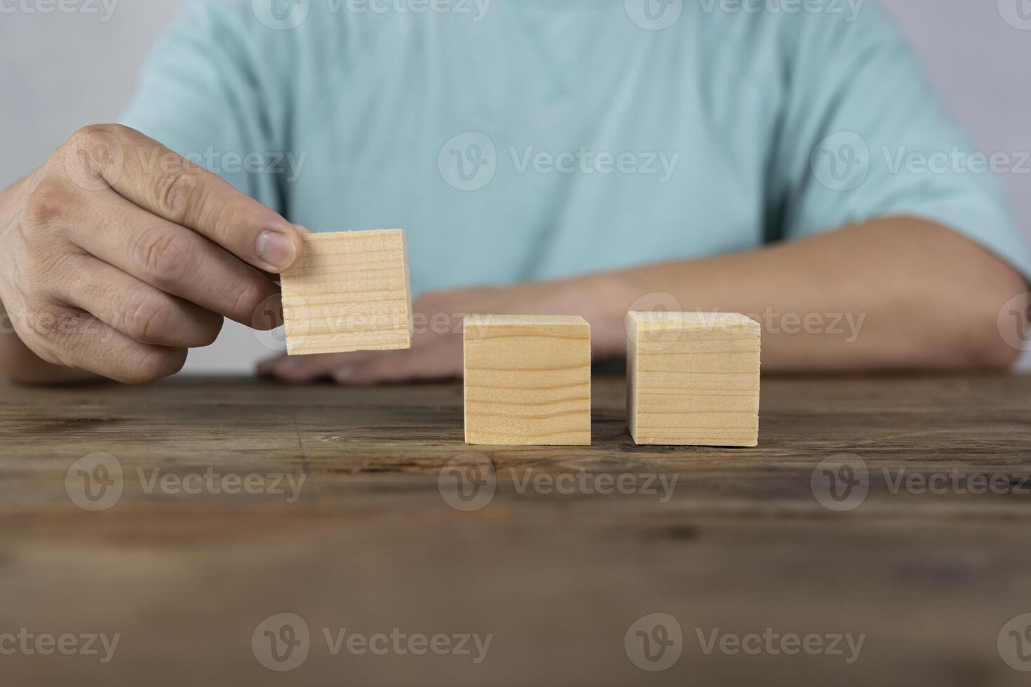 Close-up of three businessmen arranging wooden blocks Wooden toy blocks on a desk can be inserted with image text photo