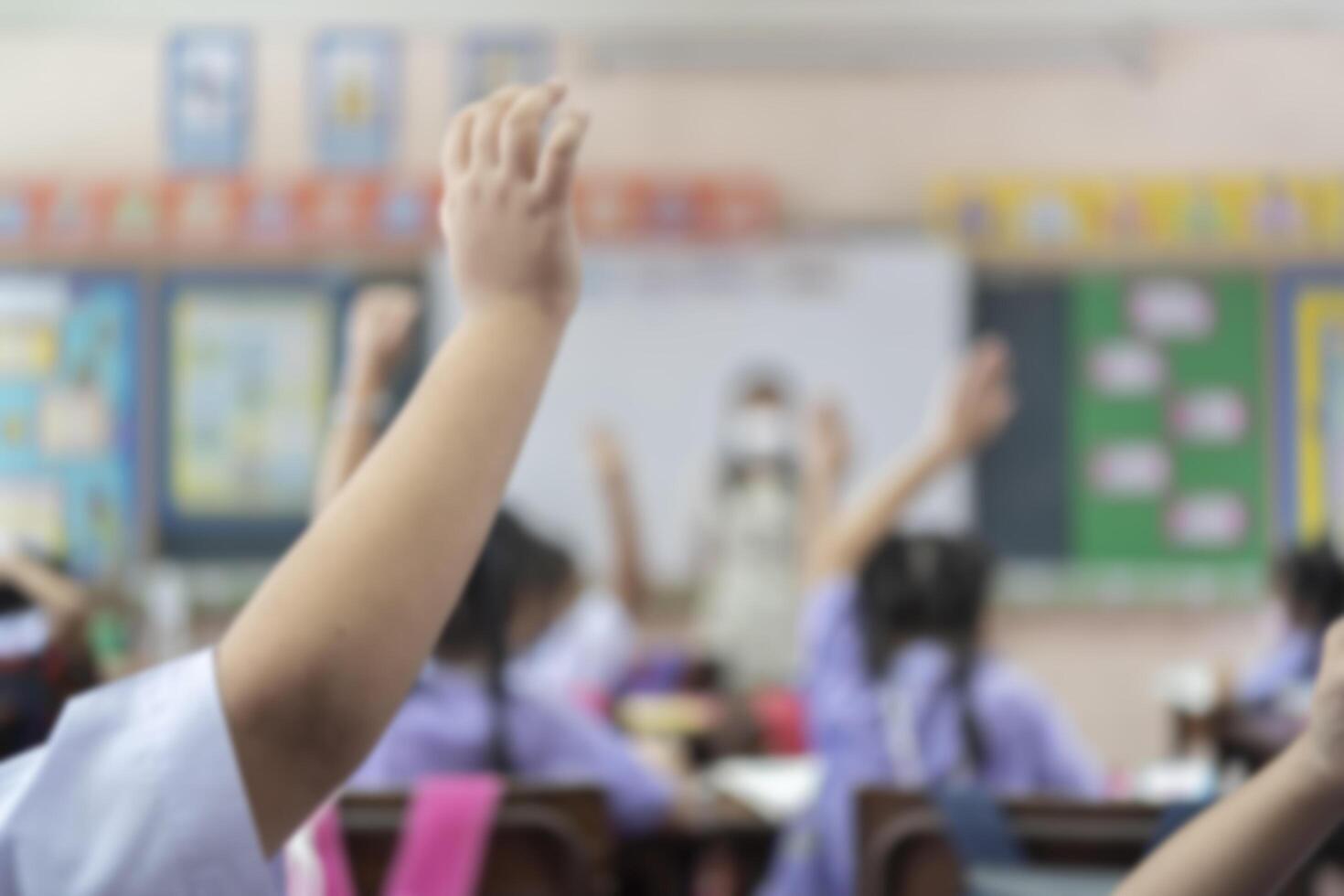 Blurred of elementary school student is raising their hands to ask the teacher standing photo