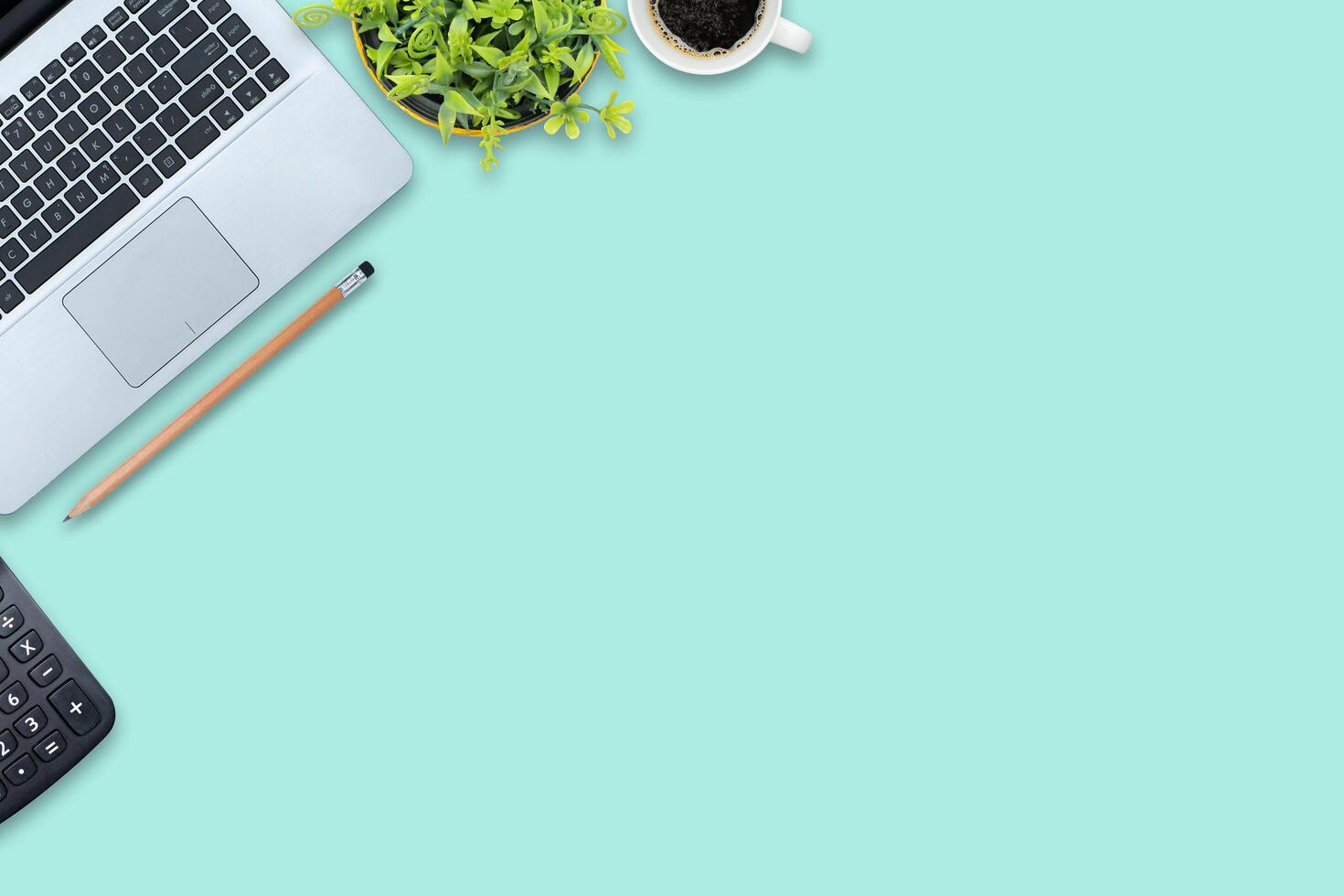 Stylish office table desk. Workspace with laptop, calculator, blank notebook and pencils on pastel green background. photo