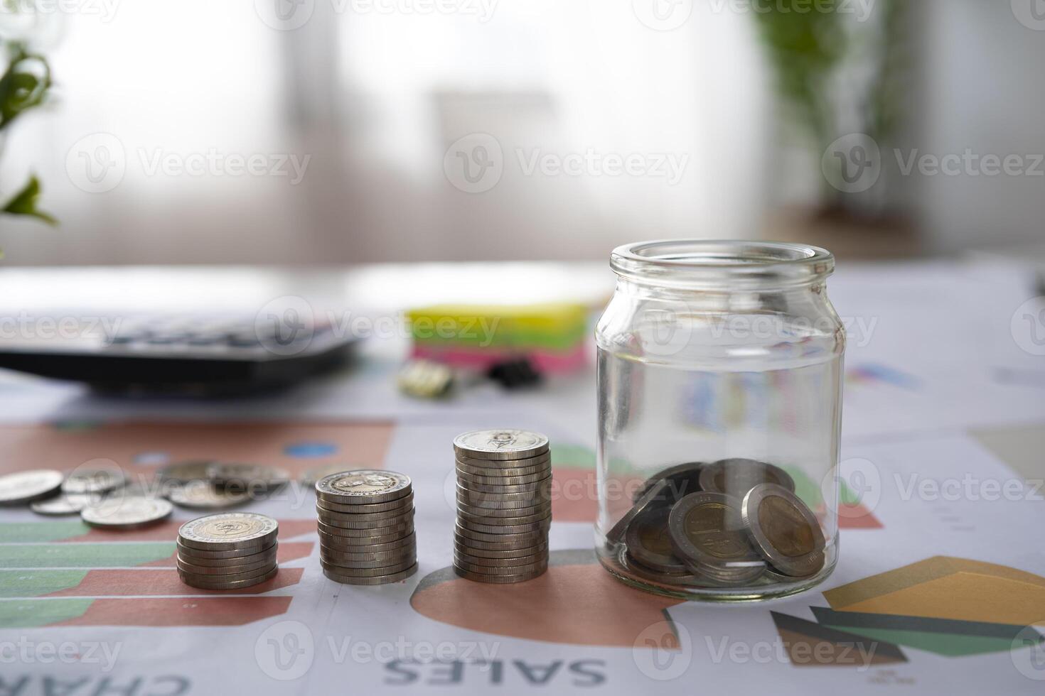 Pile of silver coins with graph paper and a calculator on a wooden table. account concept Finance and business growth photo