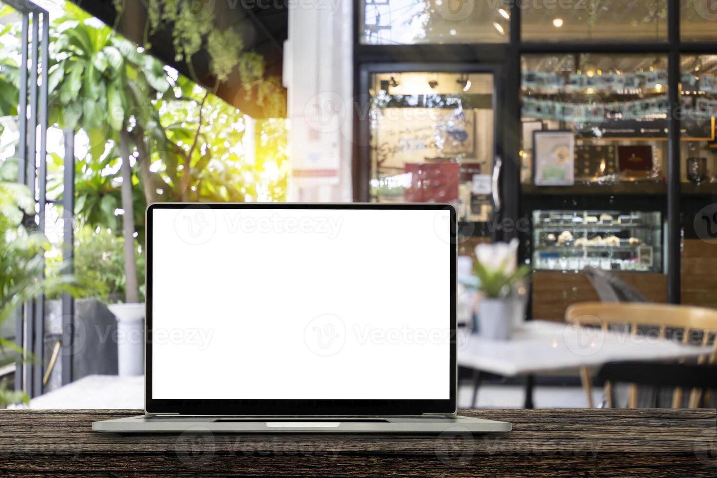 Blank screen laptop computer on wood table top with blur cafe restaurant with abstract bokeh light defocused photo