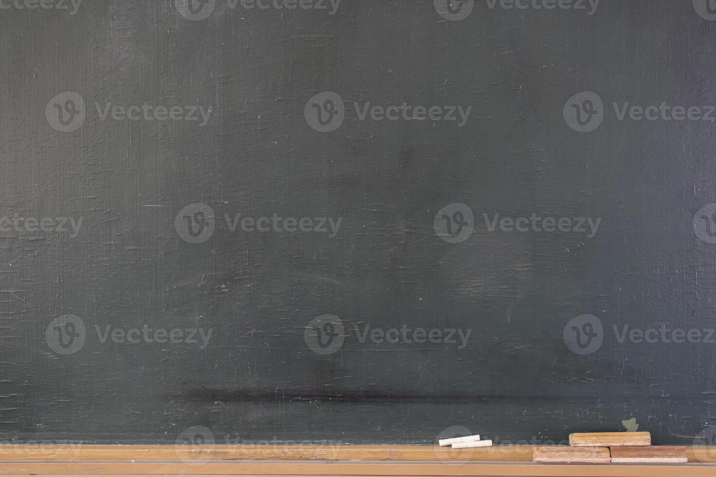Blank blackboard with colored chalks and eraser and light effect. photo