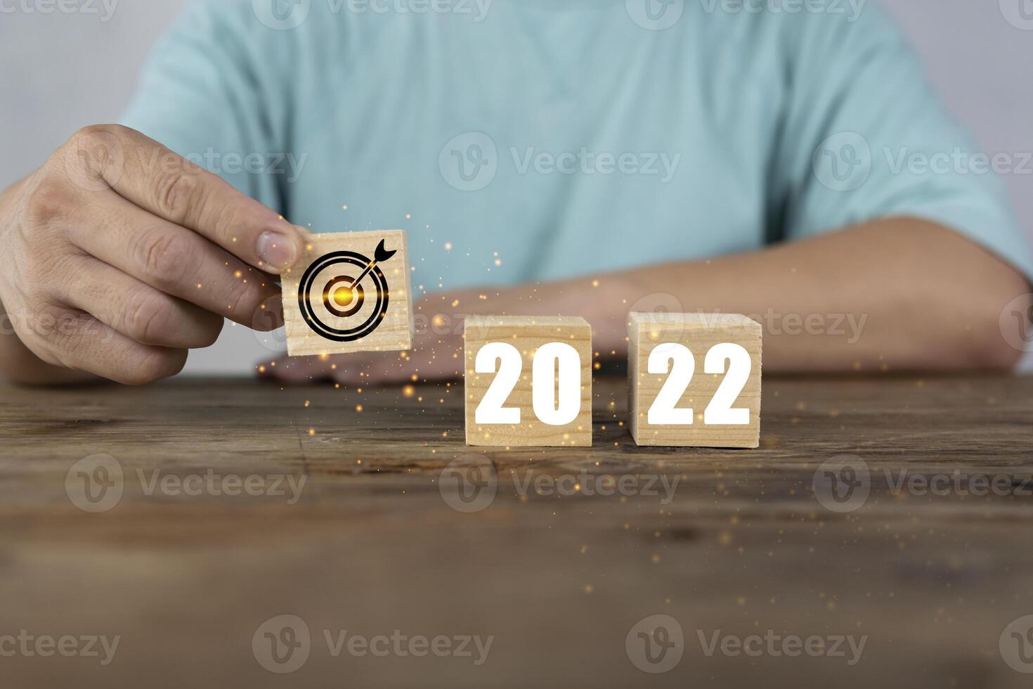 Hand putting wooden cubes 2022 with goal icon on table and white background, copy space. Start new year 2022 with goal plan, goal concept photo