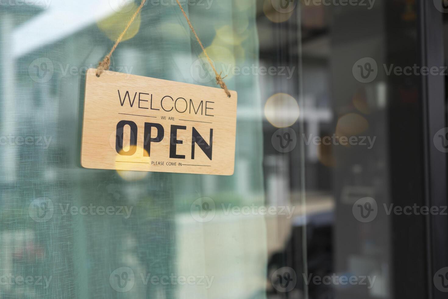Open and closed flip sign in front of coffee shop and restaurant glass door. Wooden sign with wording of place's status. Say Welcome. photo