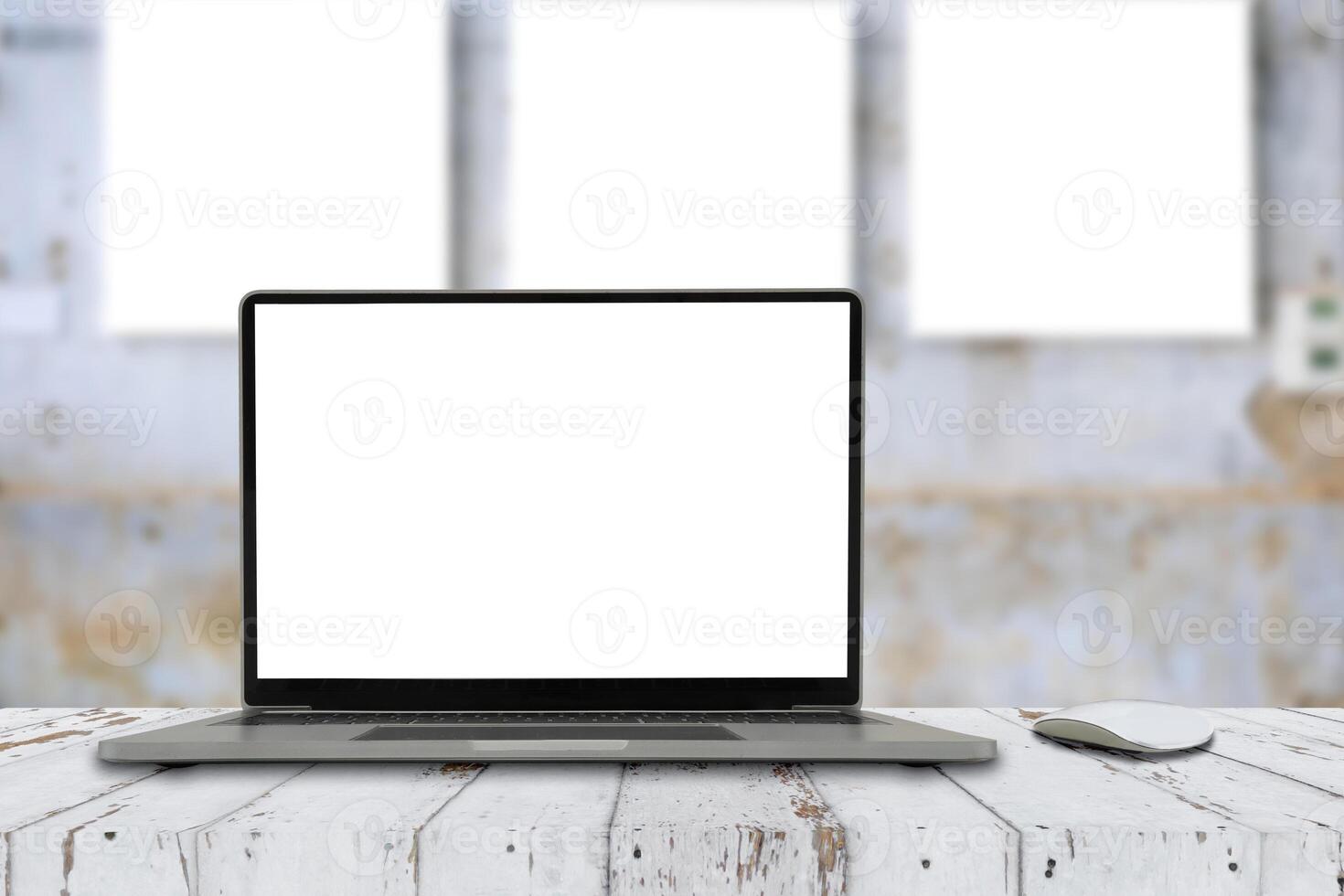 Laptop with blank screen and wireless mouse on table, office blur background photo