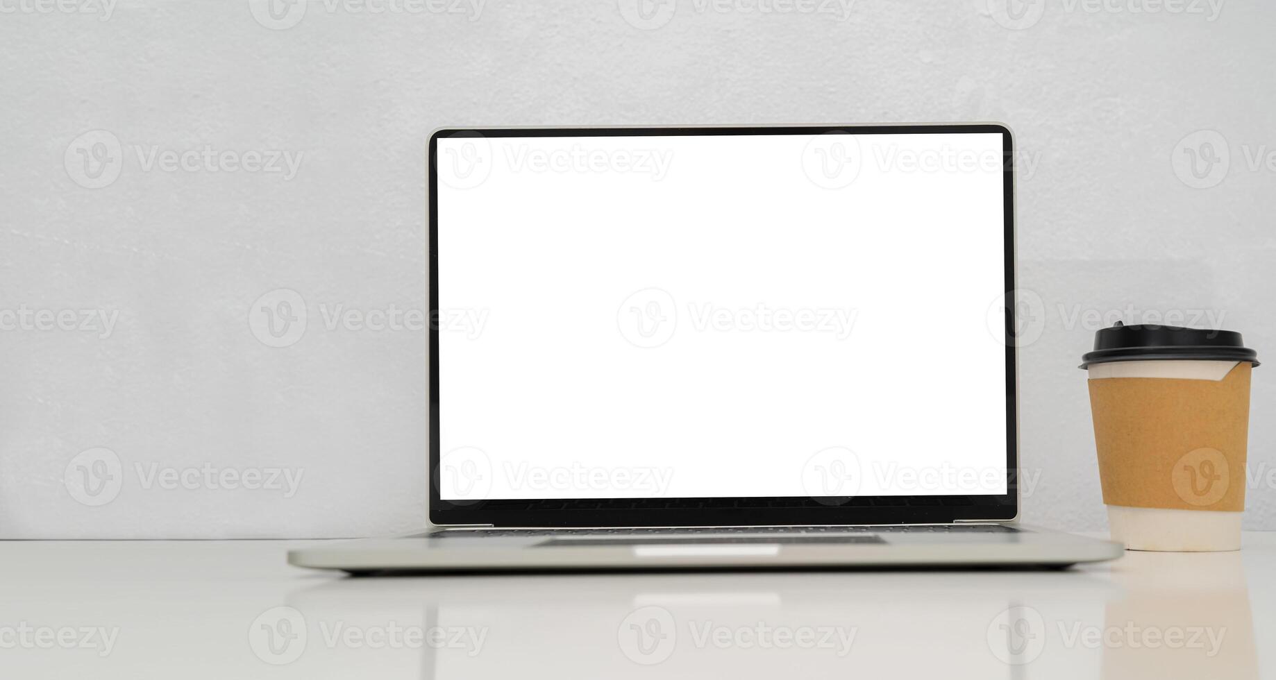 Mockup of laptop with blank white screen on table with coffee cup photo