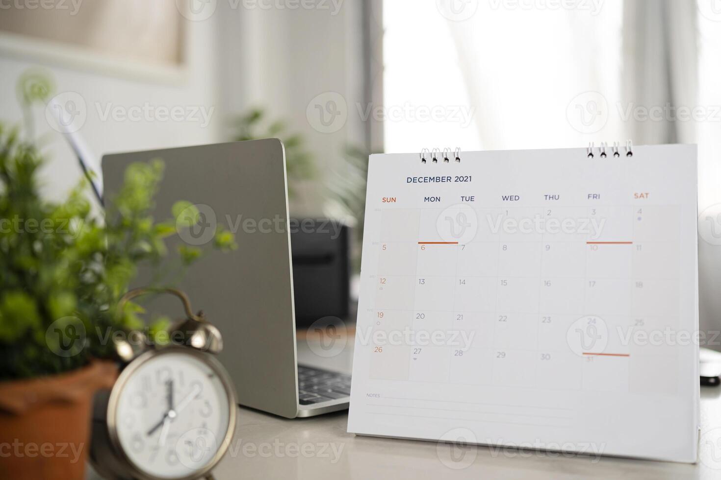 Simple desk calendar for December 2021 on workplace background. photo