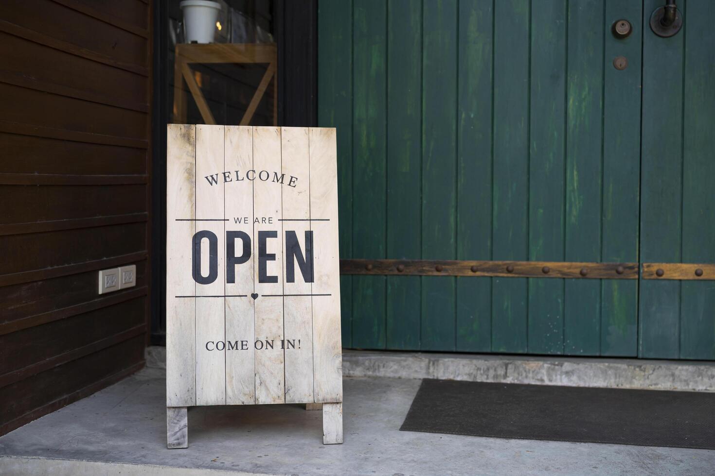 A wooden sign with the word welcome, open the sign on the door of the shop photo