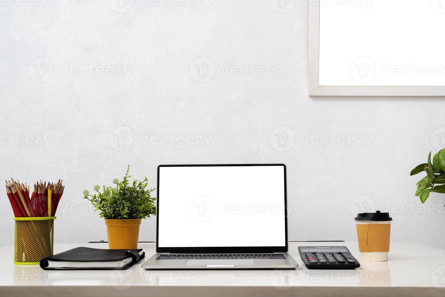 Laptop computer with blank screen, home plant, watering can, unrecognizable picture in frame on dresser. photo